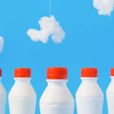 Milk bottles under a faux sky of blue paint and cotton clouds on string