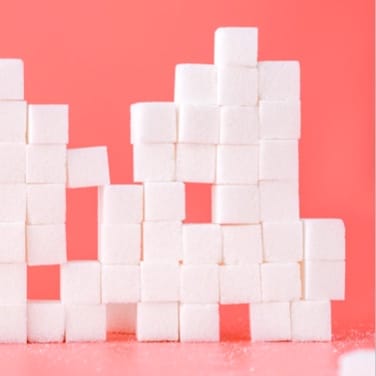 A pink background with artfully stacked sugar cubes in front of it